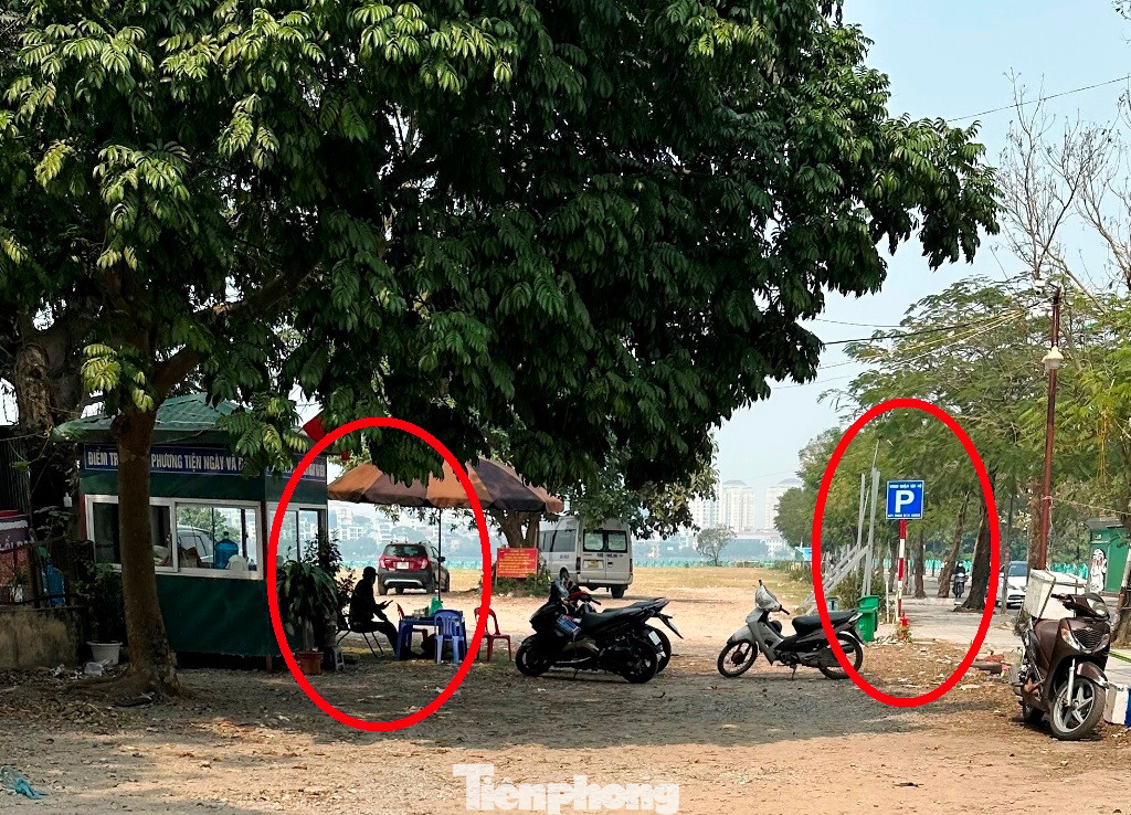 Hiện nay, trong bãi vẫn còn nhiều cột thông báo điểm trông giữ xe được UBND quận Tây Hồ cấp phép (ảnh trên) và cổng ra vào bãi xe vẫn có nhân viên ngồi đón xe, thu tiền (vòng tròn, ảnh dưới).