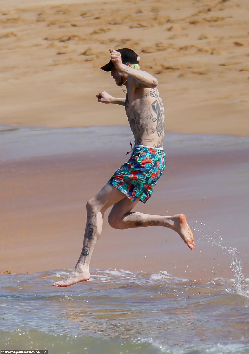 Pete Davidson gây chú ý với chiếc quần bơi sặc sỡ và thân hình phủ kín hình xăm, cùng mái tóc xanh nón chuối được giấu dưới mũ lưỡi trai đen. Ảnh: BackGrid.