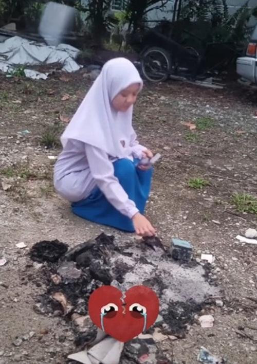 Nữ sinh ngồi bới đống tro để tìm mấy tấm ảnh còn sót lại. Ảnh: Twitter.