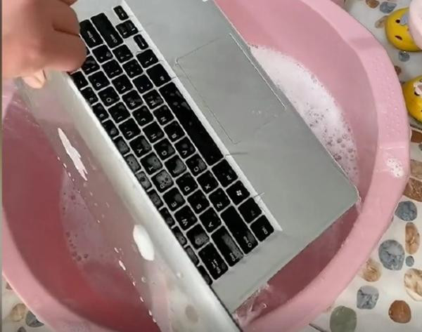 Người mẹ vớt chiếc máy từ chậu nước ra. Ảnh: Weibo. Người mẹ vớt chiếc máy từ chậu nước ra. Ảnh: Weibo.