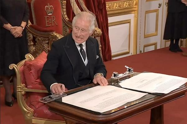 Khoảnh khắc Vua Charles III bực mình vì trợ lý không hiểu ý, cứ để hộp bút vướng tay ông. Ảnh: Reuters.