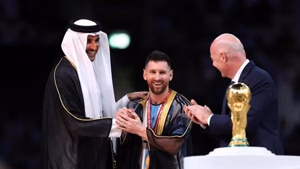 Messi được khoác cho chiếc áo choàng lạ mắt trước khi nâng cúp. Ảnh: Clive Brunskill/ Getty Images.