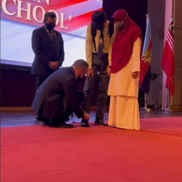 Ông Hishammuddin buộc dây giày cho học sinh lên nhận phần thưởng. Ảnh: Facebook. Ông Hishammuddin buộc dây giày cho học sinh lên nhận phần thưởng. Ảnh: Facebook.