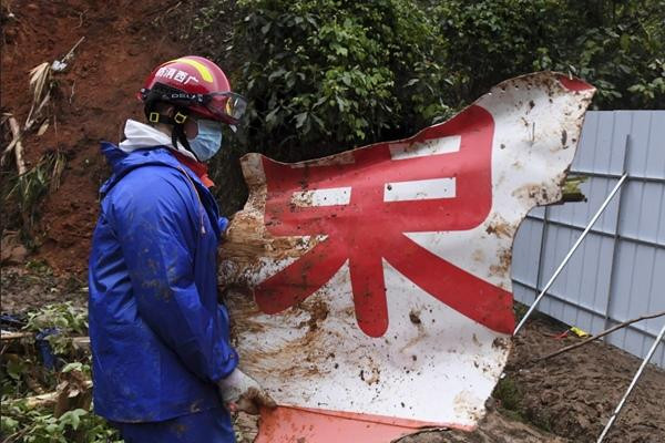 Một nhân viên cứu hộ bê một mảnh vỡ của máy bay. Ảnh: AP.