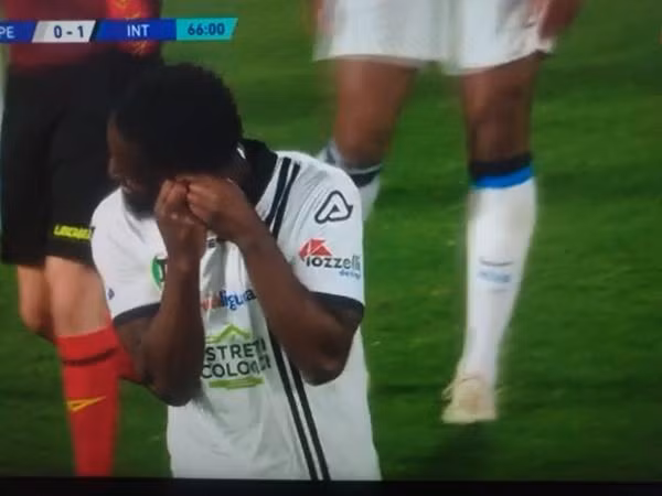 Nzola cố tháo khuyên tai của mình. Ảnh: Football Italia.