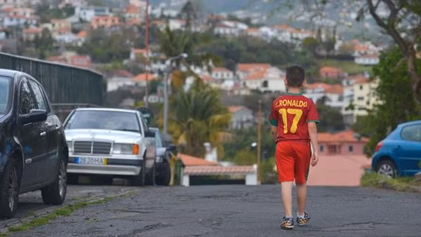 Một cậu bé mặc áo Ronaldo, đi ngang khu vực nơi Ronaldo từng sống. Ảnh: Sky Sports.