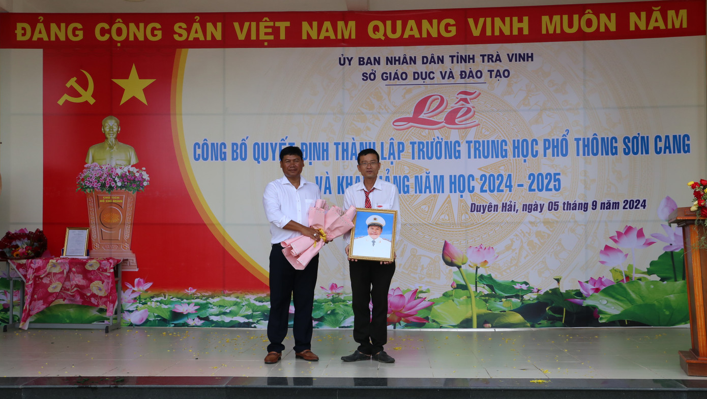 Ông Sơn Chí Hùng (bên trái, con Trung tướng Sơn Cang) tặng ảnh chân dung Trung tướng Sơn Cang cho nhà trường.