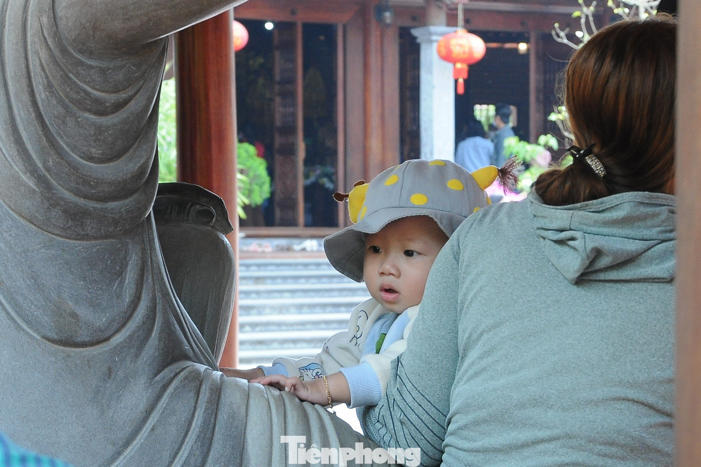 Một em bé đang "nghỉ giải lao" cùng mẹ bên tượng Phật.