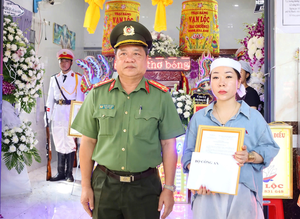 Đại tá Nguyễn Thanh Tràng - Phó Giám đốc Công an tỉnh Hậu Giang thừa ủy quyền của lãnh đạo Bộ Công an trao quyết định truy thăng cấp bậc hàm, tiền hỗ trợ của Bộ Công an cho vợ Thiếu tá Kha.