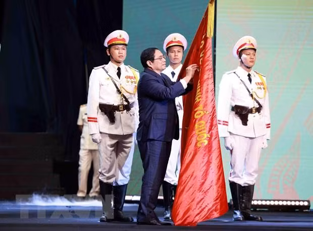 Thủ tướng Phạm Minh Chính gắn Huân chương Hồ Chí Minh lên lá cờ truyền thống của lực lượng Cảnh sát Nhân dân, Bộ Công an. (Ảnh:TTXVN)