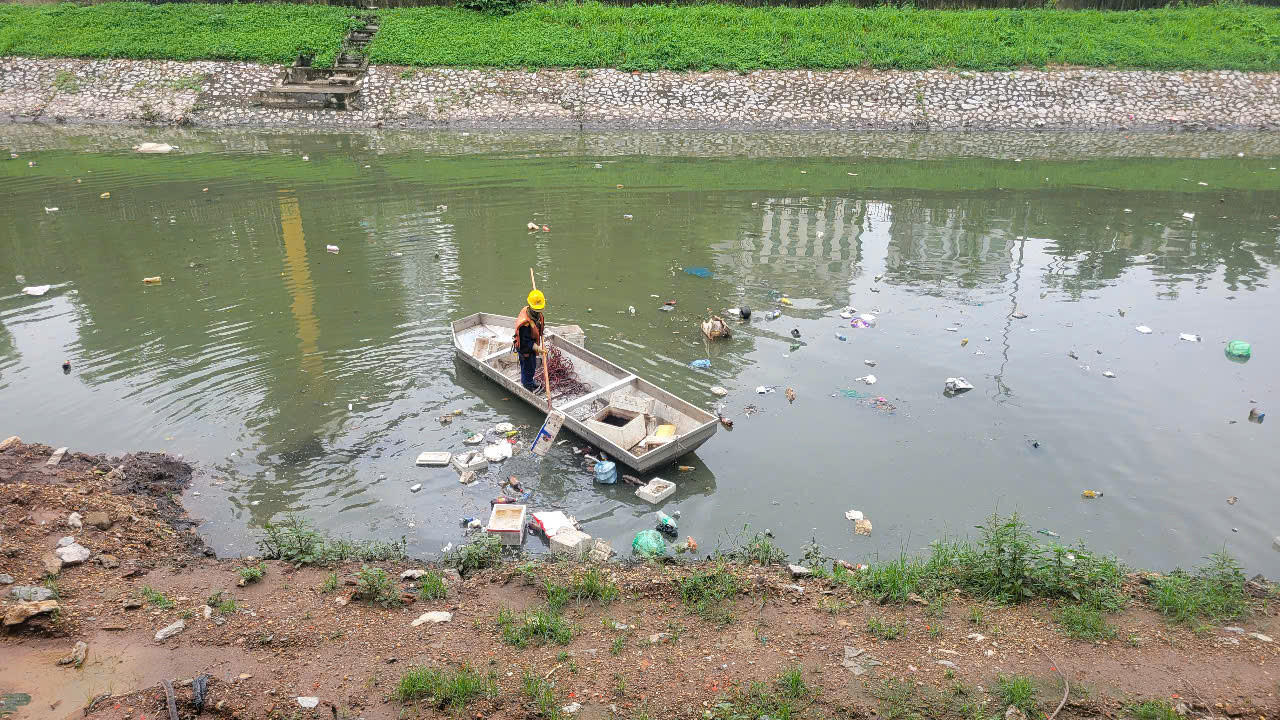 Đại diện Công ty TNHH MTV thoát nước Hà Nội thông tin thêm, sau các trận mưa lớn, rác phế thải thường từ các cống dân sinh chảy xuống sông thông qua nước mưa. Đặc biệt các loại rác nhựa, theo dòng nước mưa chảy xuống cống và trôi ra sông nên có tình trạng rác nổi lềnh bềnh trên mặt sông. Trong ảnh: Công nhân dùng thuyền để vớt rác tràn từ thượng nguồn xuống sông Tô Lịch.