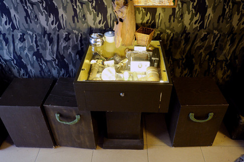 Chạy dọc quán là hai hàng bàn ghế ngồi được thiết kế lạ mắt. Vừa ngồi uống nước khách có thể tận mắt ngắm các kỷ vật trưng bày trong chiếc tủ cũng là mặt bàn được phủ kính, bố trí đèn