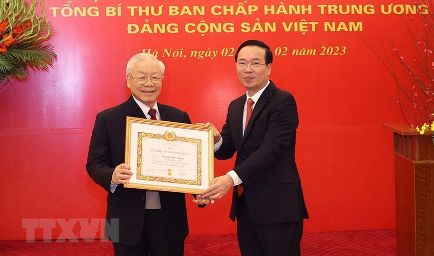 Thường trực Ban Bí thư Võ Văn Thưởng trân trọng trao Huy hiệu 55 năm tuổi Đảng và tặng hoa chúc mừng Tổng Bí thư Nguyễn Phú Trọng. Ảnh: TTXVN