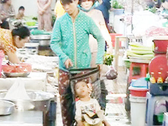 Bà Phúc đẩy xe đưa cháu bé đi ăn xin trong chợ