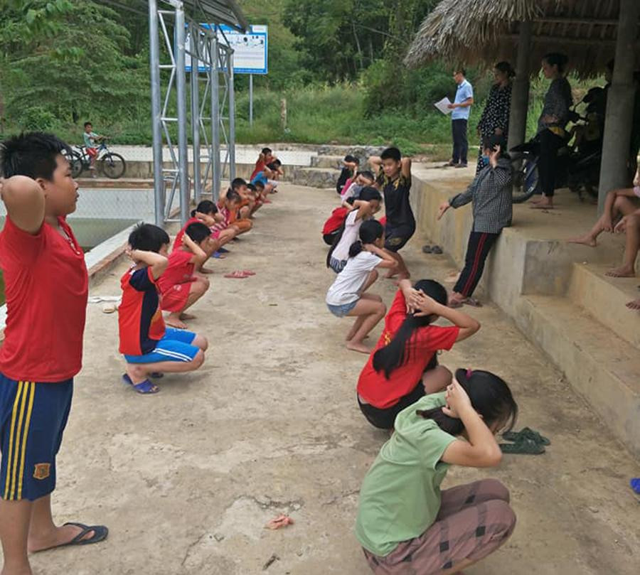 Các em khởi động để chuẩn bị bước vào một buổi tập bơi được dạy miễn phí ở huyện Như Xuân, Thanh Hoá.