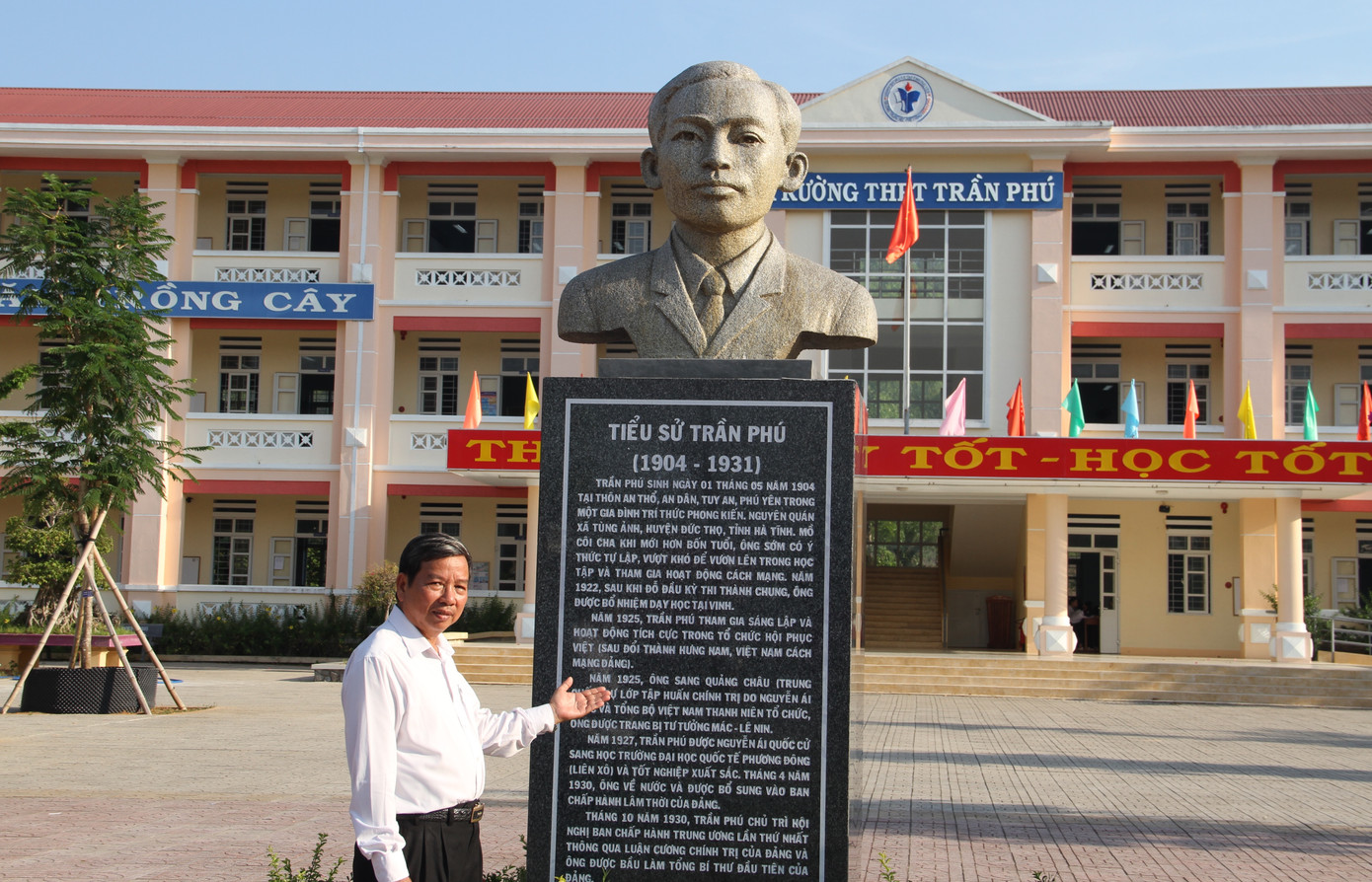 Ông Nguyễn Tấn Lập giới thiệu về Trường THPT Trần Phú bên tượng đồng chí Trần Phú.