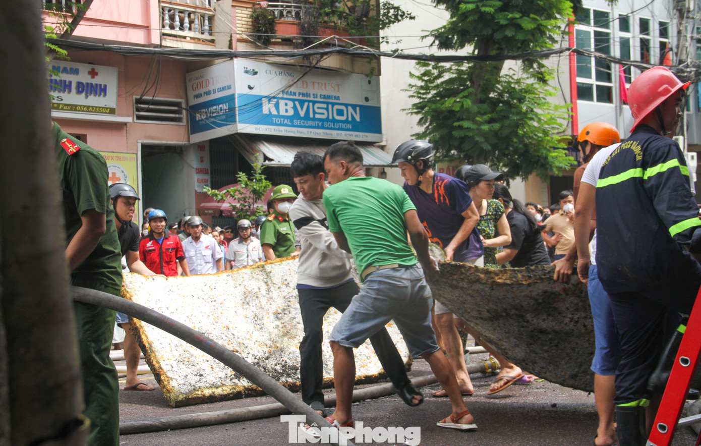 Người dân hỗ trợ di chuyển những tấm nệm bên trong căn nhà bị cháy ra ngoài. Ảnh: Trương Định