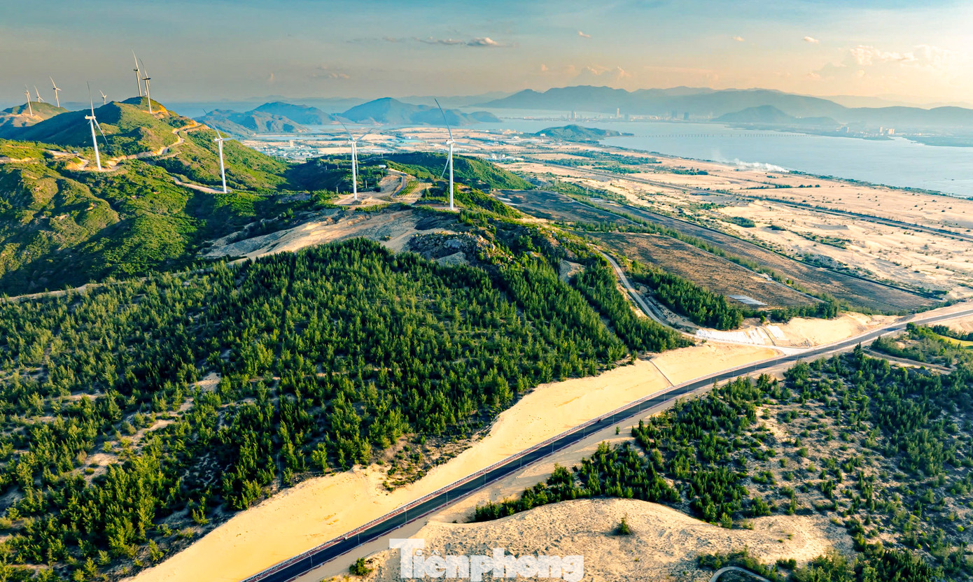 Nhìn từ trên cao, con đường đẹp như tranh vẽ khi chạy xuyên qua những đồi cát vàng óng, dọc tuyến là màu xanh cùng những cánh rừng phi lao và những cột điện gió khổng lồ. Ảnh: Dũng Nhân.