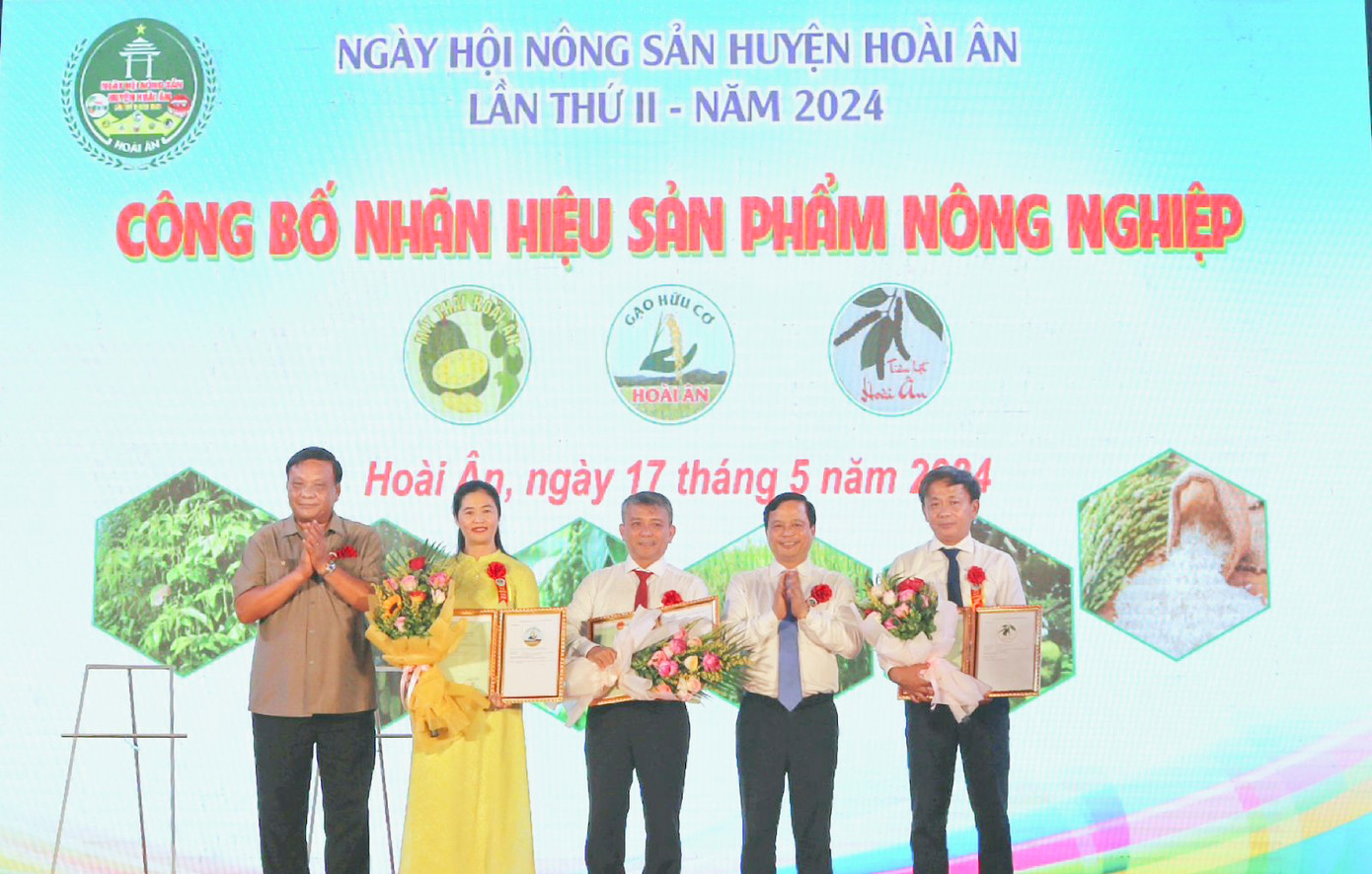 Lãnh đạo tỉnh Bình Định trao giấy chứng nhận của Cục Sở hữu trí tuệ về đăng ký nhãn hiệu sản phẩm cho huyện Hoài Ân. Ảnh: K.L