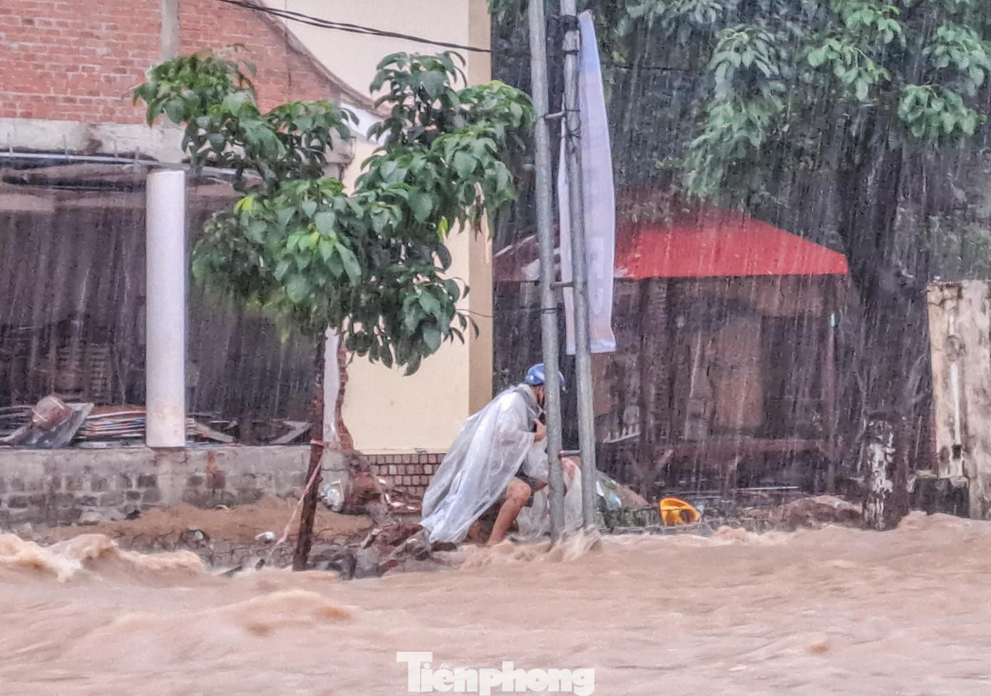 Một người đàn ông bị mắc kẹt giữa dòng nước dữ trên đường Hàn Mặc Tử, phường Ghềnh Ráng. Ảnh: Trương Định
