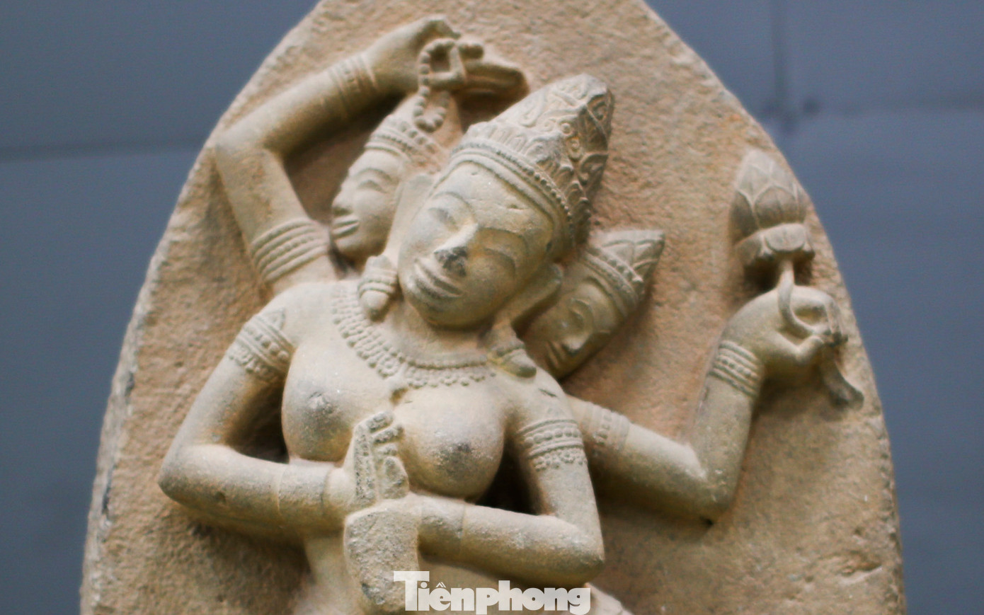 Nữ thần Sarasvati - vợ của thần Brahma - là nữ thần sáng tạo ra tiếng Phạn, nữ thần của thi ca và nghệ thuật. Hình tượng thể hiện trên phù điêu là nữ thần được tạc nổi trong vòm cung nhọn (tấm lá nhĩ), nữ thần có ba đầu đều đội mũ hình chóp viền dải băng ngọc và hình cánh sen, bốn tay thể hiện vũ nữ đang múa trong tư thế tam đoạn (tribhanga), hai cánh tay chính trong tư thế tĩnh, cánh tay khuỳnh ra hai bên sau đó gập khuỷu tay lại đưa ngang trước ngực và cùng cầm một chiếc bình nước. Ảnh: Trương Định.