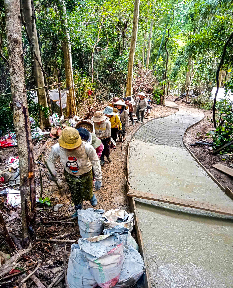 Việc vận chuyển vật liệu xây dựng như cát, sỏi, xi măng,… lên để thi công tuyến đường gặp nhiều khó khăn do địa hình dốc núi hiểm trở. Tại nhiều đoạn đường dốc đứng, người dân phải dùng gùi, cõng từng bao sỏi, cát lên núi để phục vụ thi công con đường.