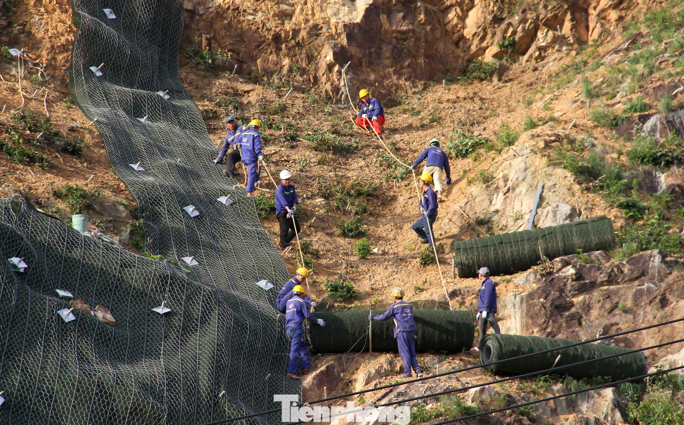 Công nhân đu dây để phủ lưới thép sức kháng cao lên bờ mặt núi Bà Hỏa. (Ảnh: Trương Định)
