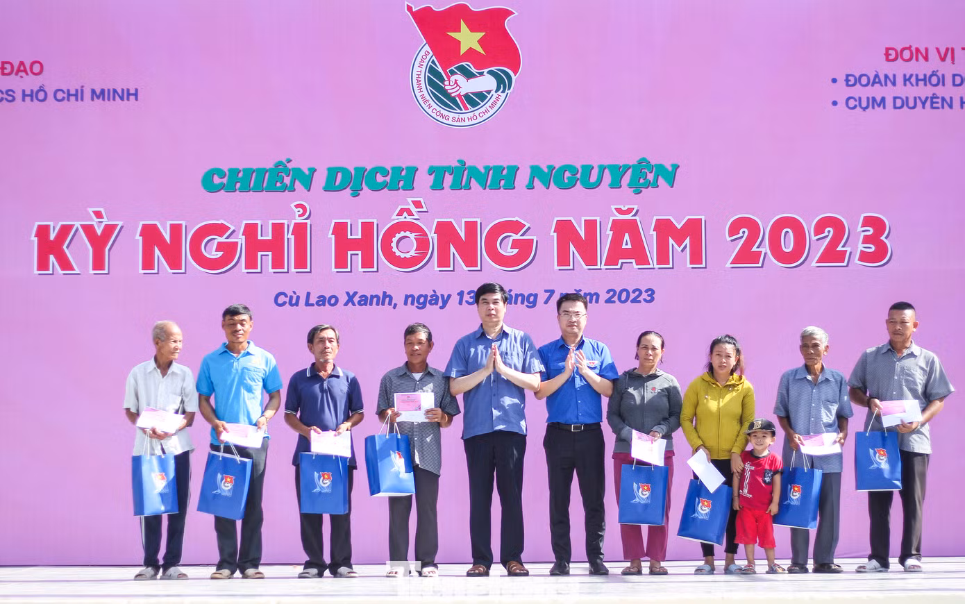 Anh Nguyễn Tường Lâm (phải) và ông Lâm Hải Giang trao quà cho các gia đình chính sách ở xã Nhơn Châu. Ảnh: Trương Định
