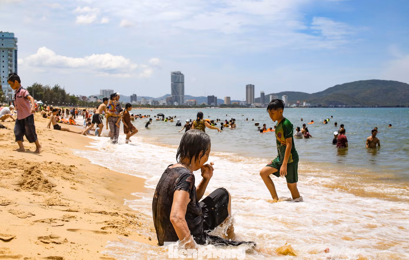 Nhiều người sau khi tắm xong không quên mang nước biển về cho người thân ở nhà. Ảnh: Trương Định.