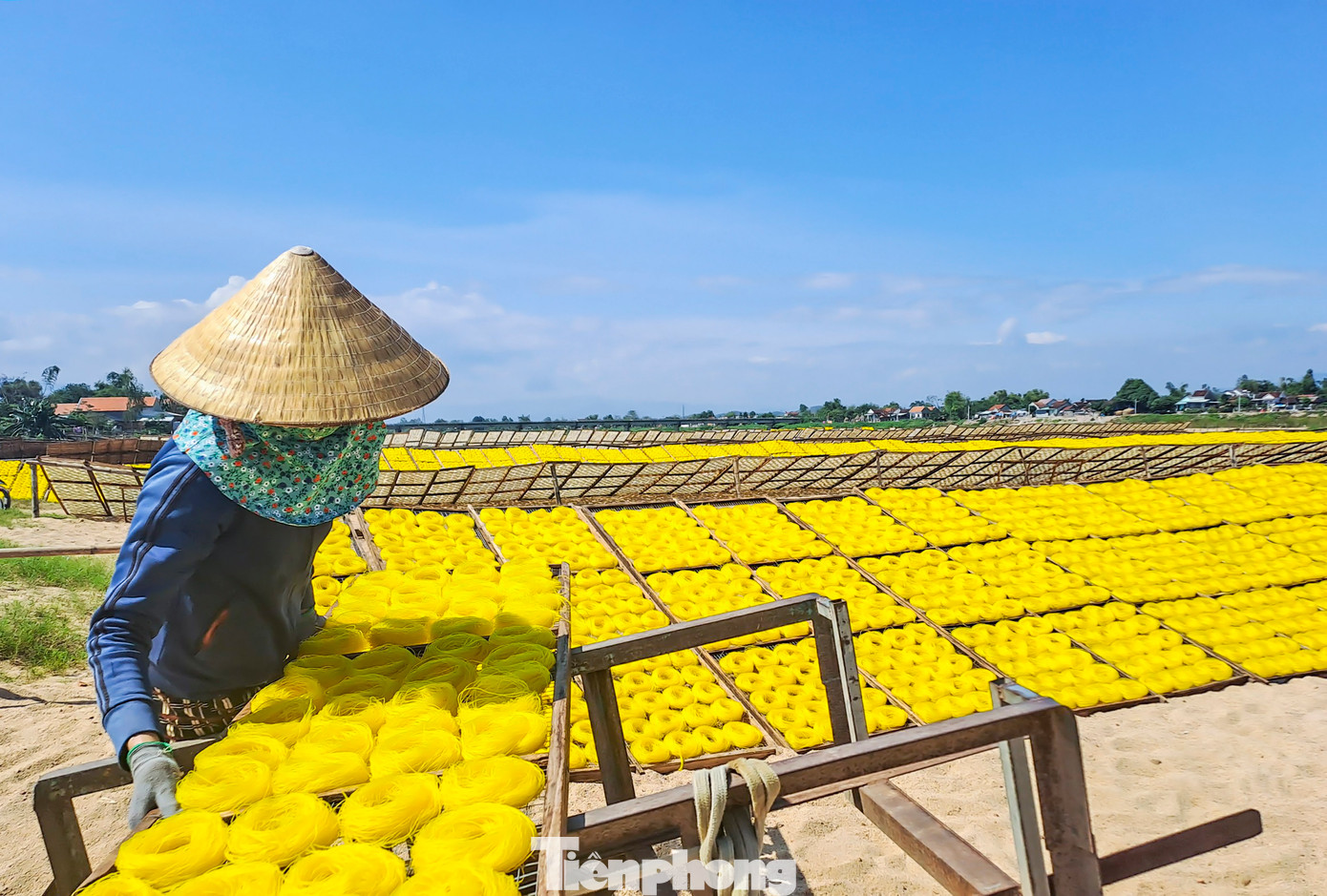 Để cho ra những sản phẩm, bắt đầu từ tờ mờ sáng, các thợ làm bánh, bún đã nhóm lửa, xay bột, đúc khuôn bánh, bún cho ra những sợi bún gạo, mì trắng mượt mà, những chiếc bánh tráng dài như miếng dải lụa mềm mại, để đưa lên vỉ tre phơi nắng trên bãi cát vàng nằm bên bờ sông Kôn (Ảnh: Trương Định).
