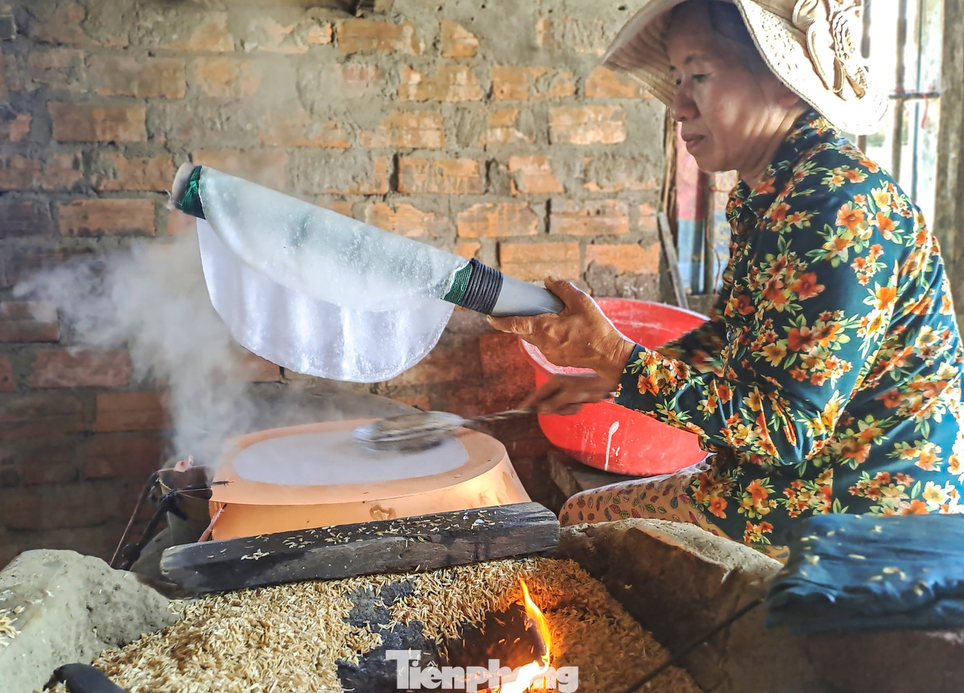 Bà Nguyễn Thị Hoa (65 tuổi, xã Nhơn Phúc) - là một trong số ít những người còn giữ nghề tráng bánh bằng phương pháp thủ công cũng đang tất bật bên bếp lửa đỏ để có hàng kịp bán dịp Tết (Ảnh: Trương Định).