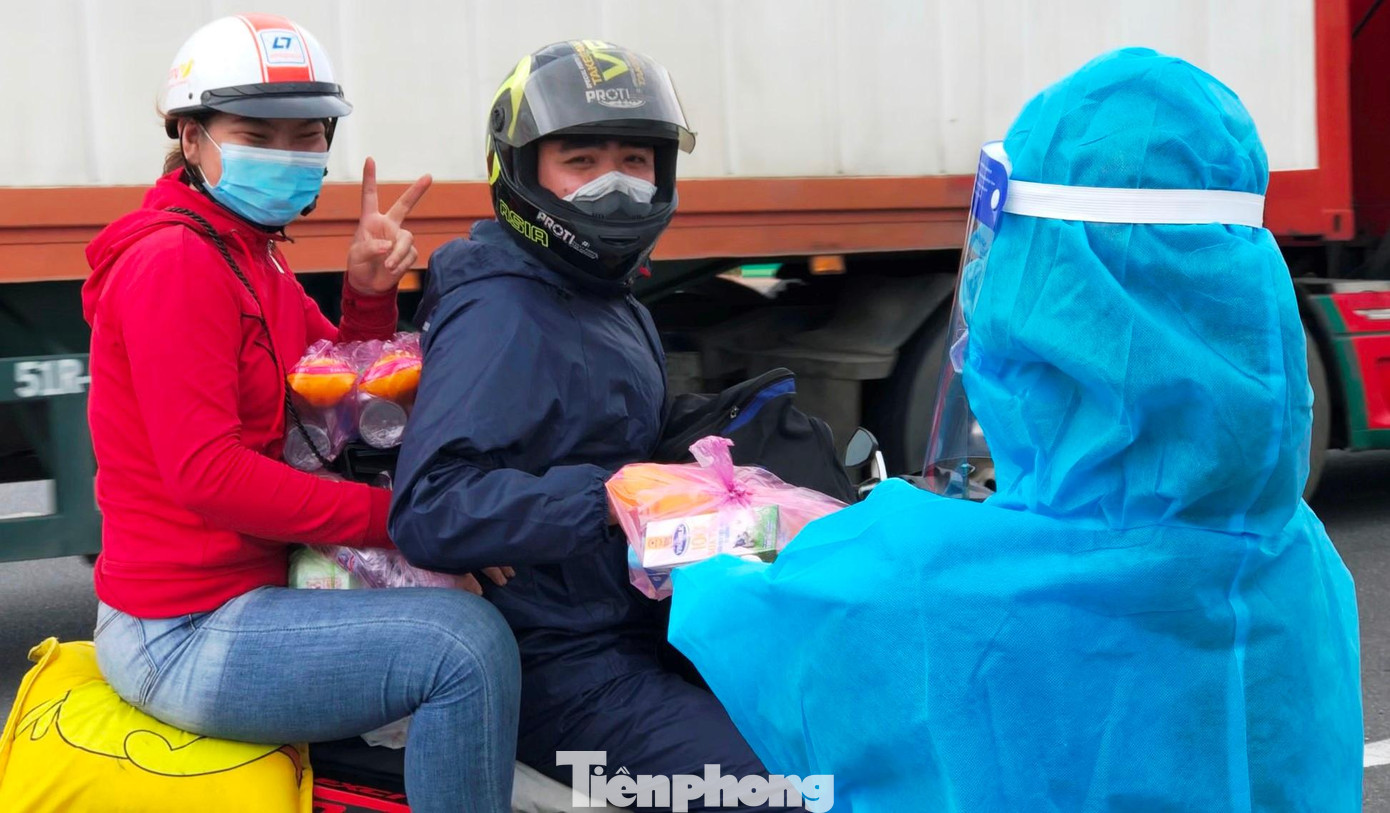 Tặng đồ ăn, nước uống cho người dân về quê tránh dịch COVID-19. Ảnh: Trương Định
