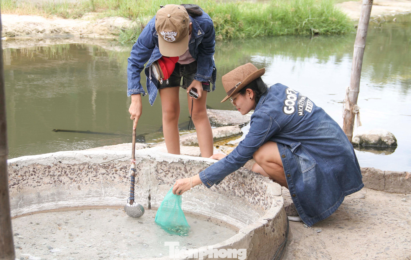 Du khách trải nghiệm luộc trứng dưới vũng nước đang sôi ùng ục. (Ảnh: Trương Định)