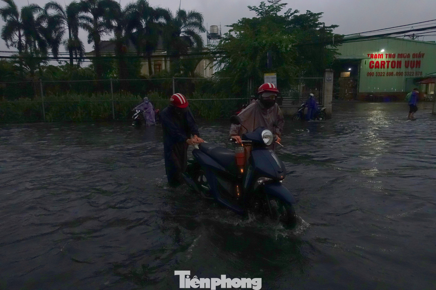 Người dân bì bõm lội nước đưa phương tiện thoát khỏi điểm ngập.