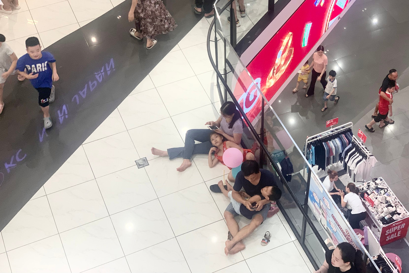 Nhiều người tranh thủ nghỉ ngơi, "trốn nắng" tại khu vực hành lang, lan can trong TTTM.