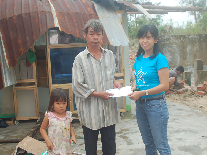 Bà Đoàn Đỗ Ngọc Thi trao quà cho ông Lưu Văn Tư trong căn nhà bị tốc mái của ông ở xã Điện Dương, Huyện Điện Bàn, Tỉnh Quảng Nam