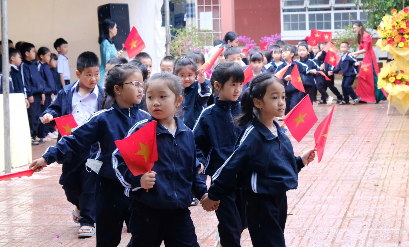 Các em học sinh phấn khởi cầm cờ diễu hành trong sân trường Các em học sinh phấn khởi cầm cờ diễu hành trong sân trường