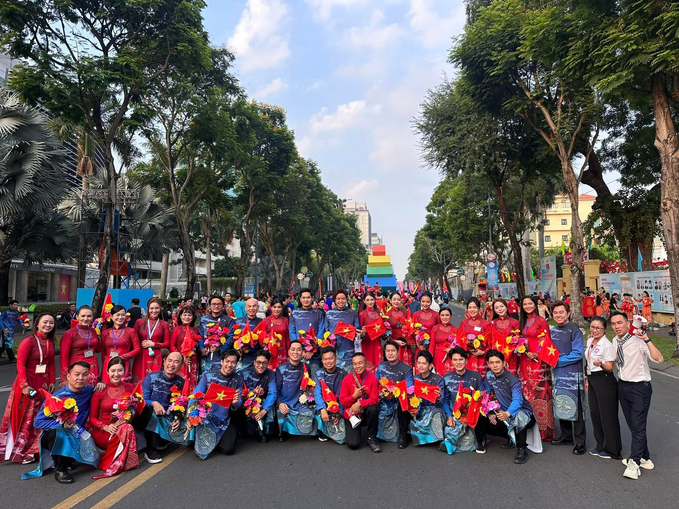 Dàn nghệ sĩ diện áo dài tham gia lễ diễu hành: Nữ áo dài đỏ rực, nam áo dài xanh với họa tiết hoa sen và nền trống đồng. - Ảnh: Ninh Dương Lan Ngọc