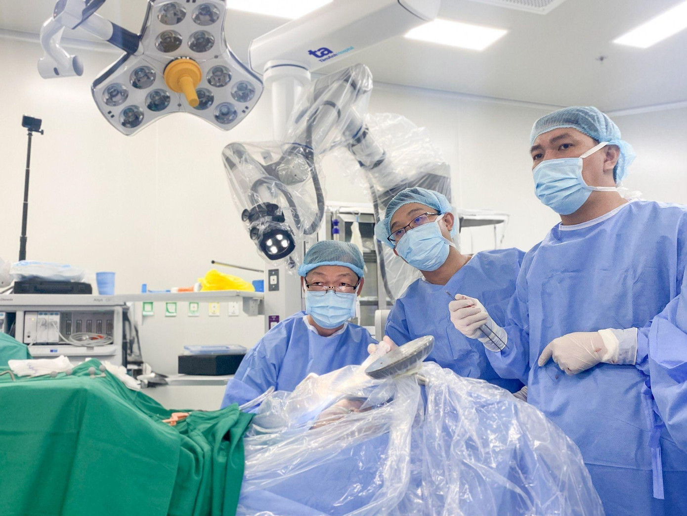 Bác sĩ Tấn Sĩ (người ngồi) và cộng sự trong ca mổ não tỉnh thức cho người bệnh bằng Robot Modus V Synaptive. Ảnh: Nguyễn Trăm. Bác sĩ Tấn Sĩ (người ngồi) và cộng sự trong ca mổ não tỉnh thức cho người bệnh bằng Robot Modus V Synaptive. Ảnh: Nguyễn Trăm.