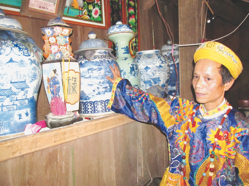 Tay chơi Alăng Linh áo gấm thêu rồng bên gia tài cổ vật. Ảnh: Nam Cường. Tay chơi Alăng Linh áo gấm thêu rồng bên gia tài cổ vật