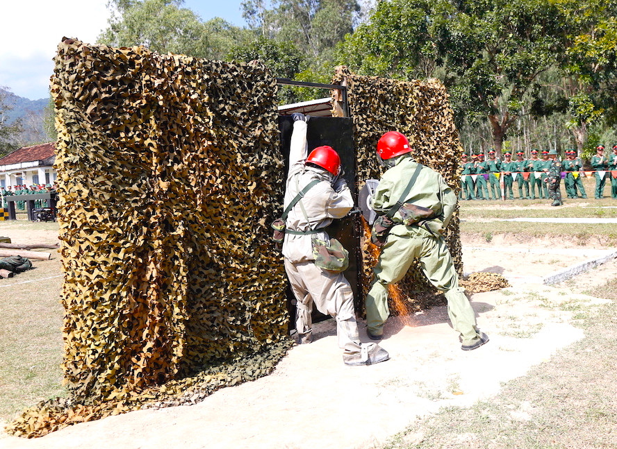 Hai vận động viên dùng cưa để cưa cánh cửa sắt cứu hộ người mắc kẹt