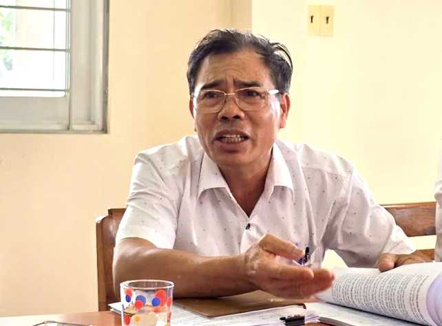 Ông Bảy trao đổi với phóng viên về việc thu bảo hiểm bằng cà phê.