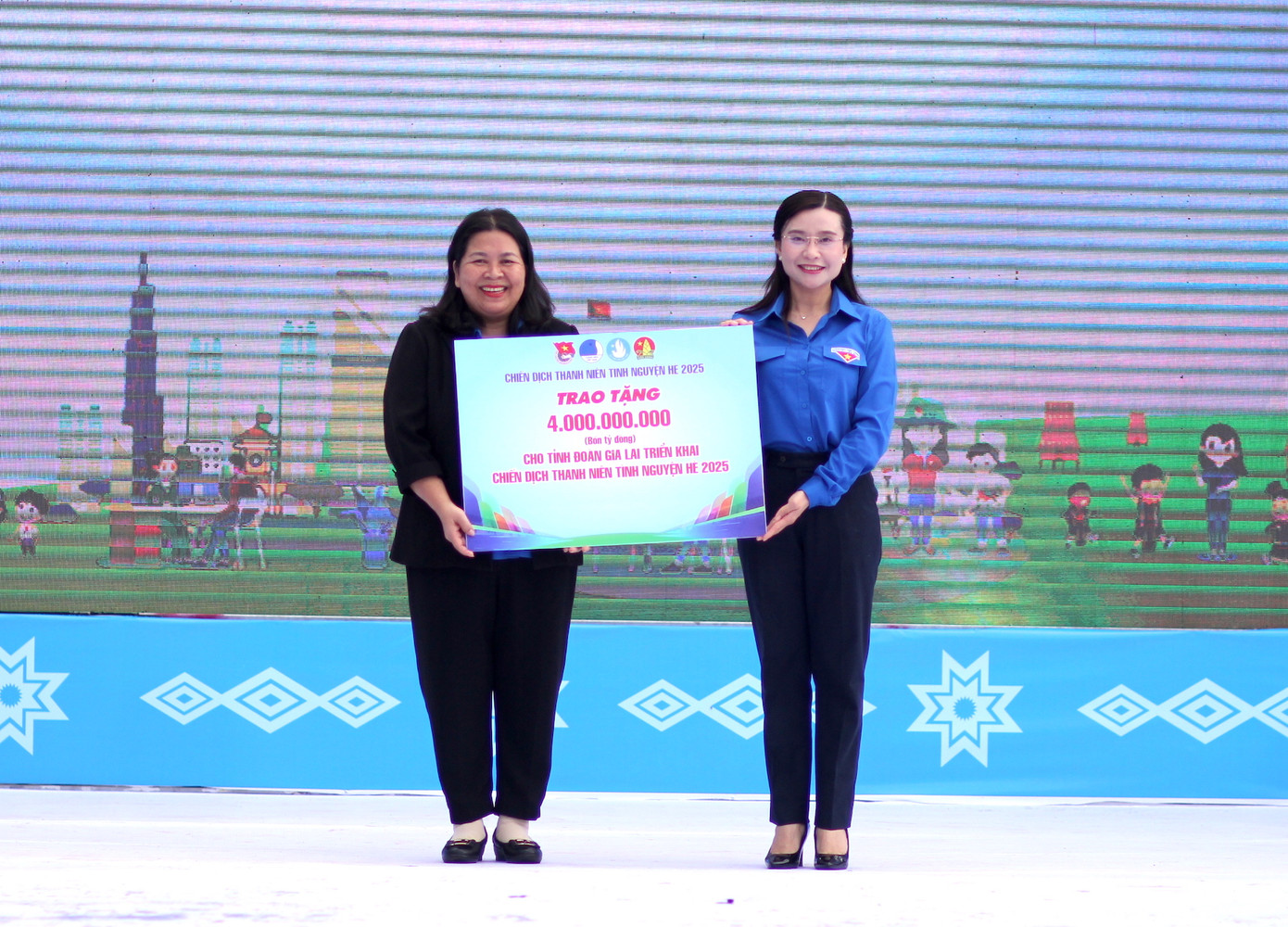 Chị Nguyễn Phạm Duy Trang (phải) trao bảng tượng trưng 4 tỷ đồng cho Bí thư Tỉnh Đoàn Gia Lai Hà Thị Giang Thảo triển khai Chiến dịch Thanh niên tình nguyện Hè năm 2025.