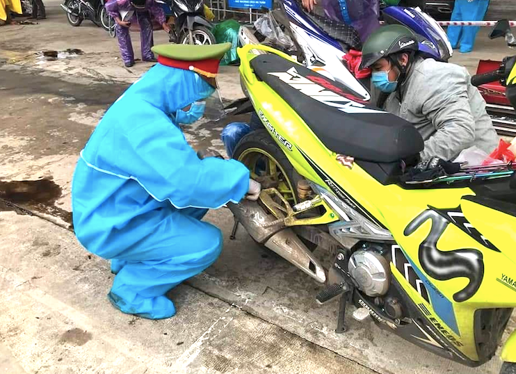 Các chiến sĩ công an trong bộ đồ bảo hộ kín mít, lấm lem dầu nhớt đang miệt mài sửa xe giúp dân.