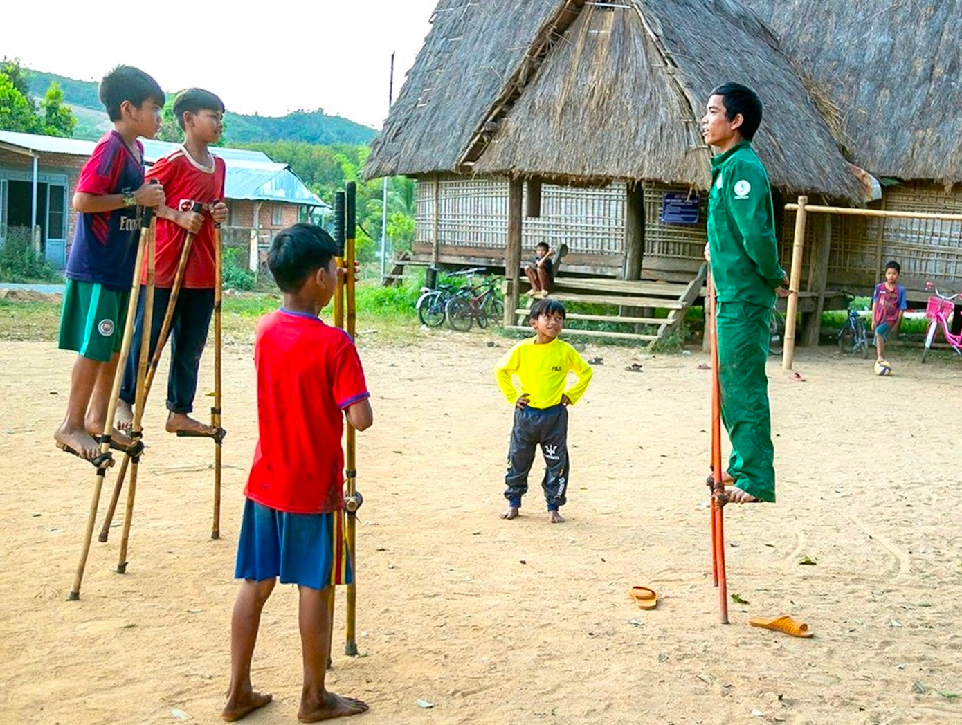Anh Tham phô diễn kỹ năng đứng trên cà kheo với các em nhỏ.