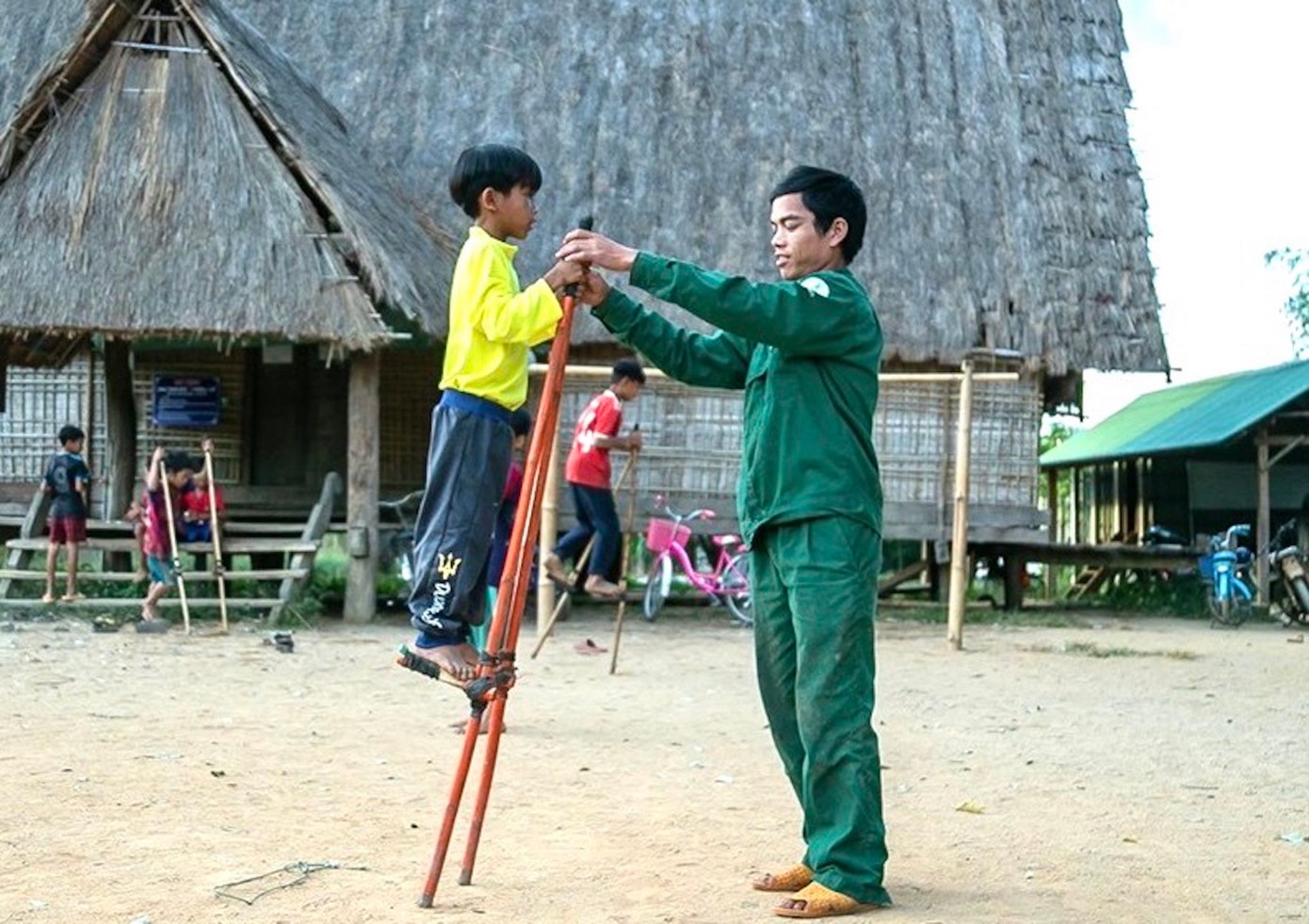 Anh Tham phô diễn kỹ năng đứng trên cà kheo với các em nhỏ.