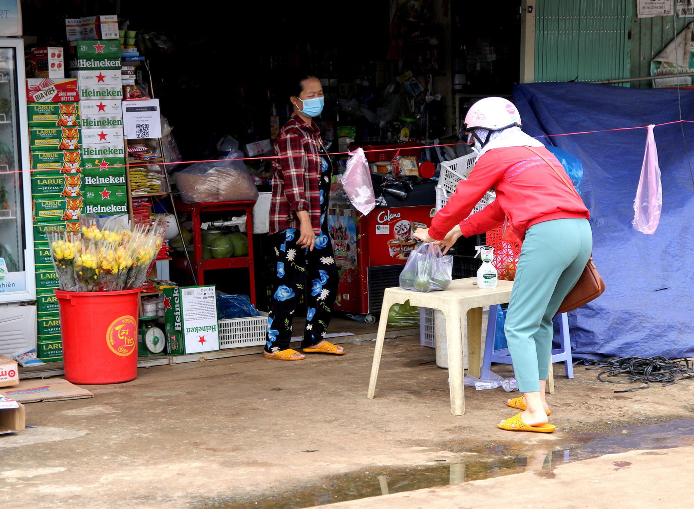 Các hàng quán được mở khi tuân thủ đúng các yêu cầu chống dịch để tránh lây lan. Trong ảnh, để tránh tiếp xúc gần với người mua hàng, chủ quán tạp hóa để thực phẩm ở một bàn sau đó khách hàng tới lấy.