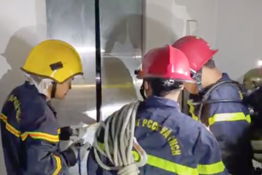 Lực lượng chức năng dùng máy banh thủy lực phá cửa thang máy. Ảnh: PC07. Lực lượng chức năng dùng máy banh thủy lực phá cửa thang máy. Ảnh: PC07.