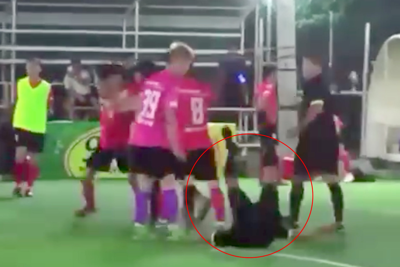 Trọng tài K (khoanh tròn đỏ) ngã gục trên sân sau khi bị đánh vào mặt. Ảnh cắt từ clip.