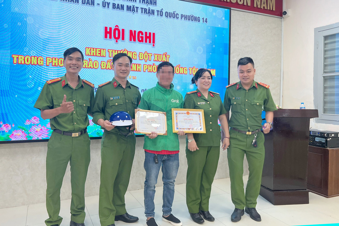 Trung tá Nguyễn Thị Gái, Trưởng Công an phường 14 (thứ 2 từ phải qua) trao giấy khen cho tài xế xe ôm công nghệ. Ảnh: H.T.